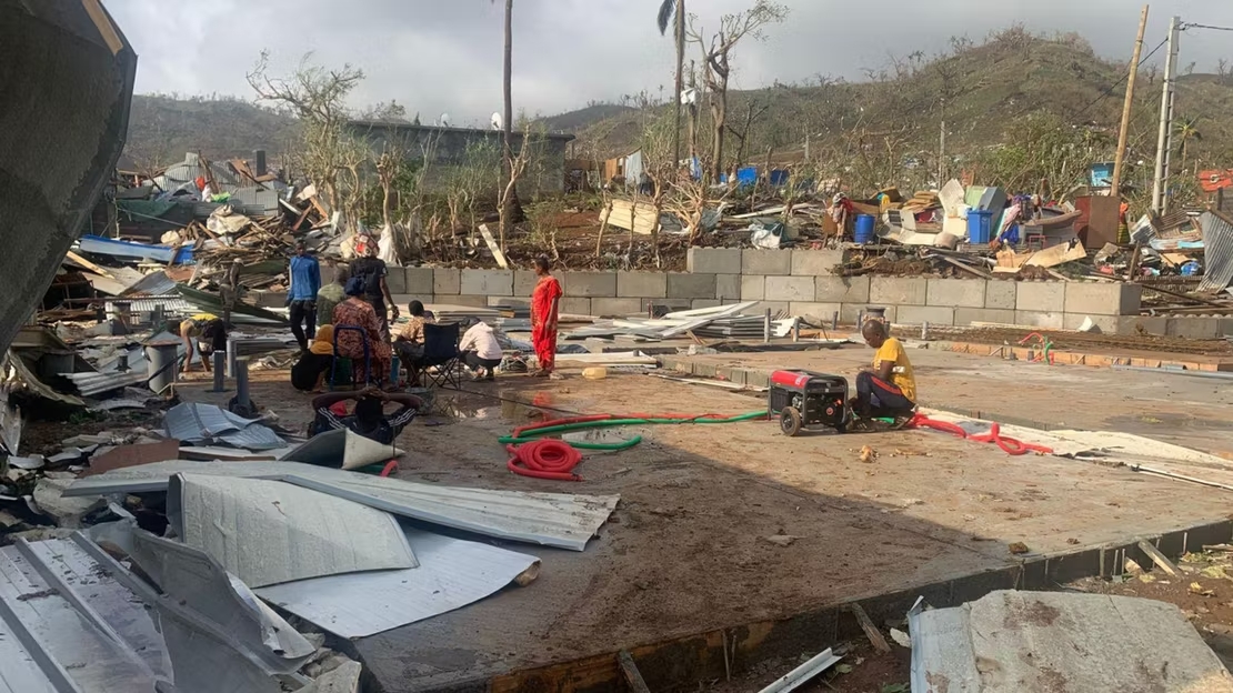 ©KWEZI-AFP Des Mahorais devant les ruines de bois et de tôles de leurs maisons, détruites par le cyclone Chido. Mayotte, le 15 décembre 2024. ©KWEZI-AFP