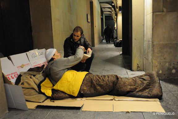 un bénévole de l'équipe de la maraude donne un livre à une personne sans-abri