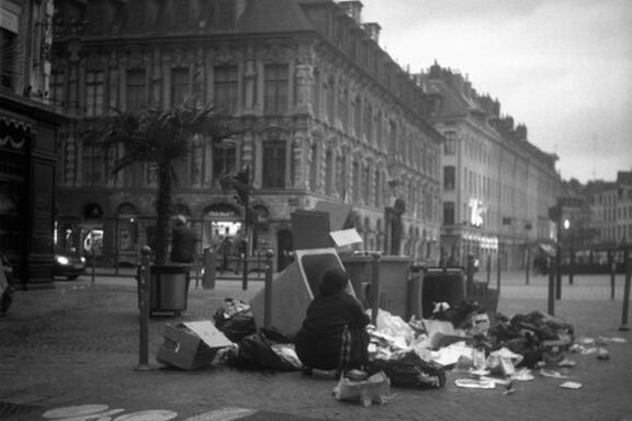 Une femme à Lille fouille les poubelles.