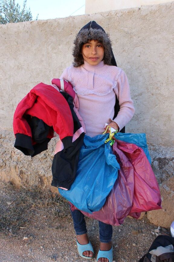 Une petite fille reçoit un manteau d'hiver, à Zaatari (Jordanie)